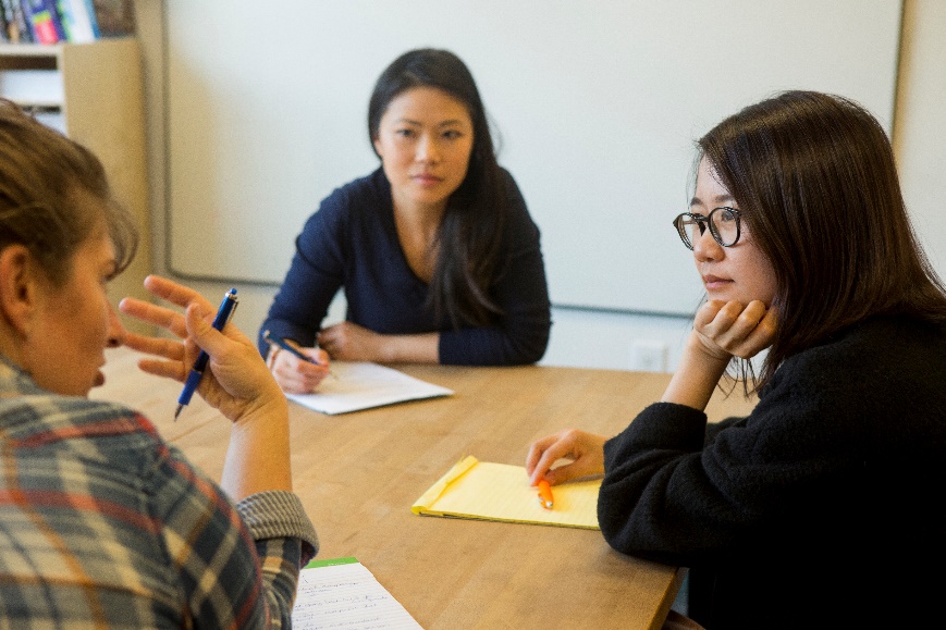 Three people around a table at a meeting 