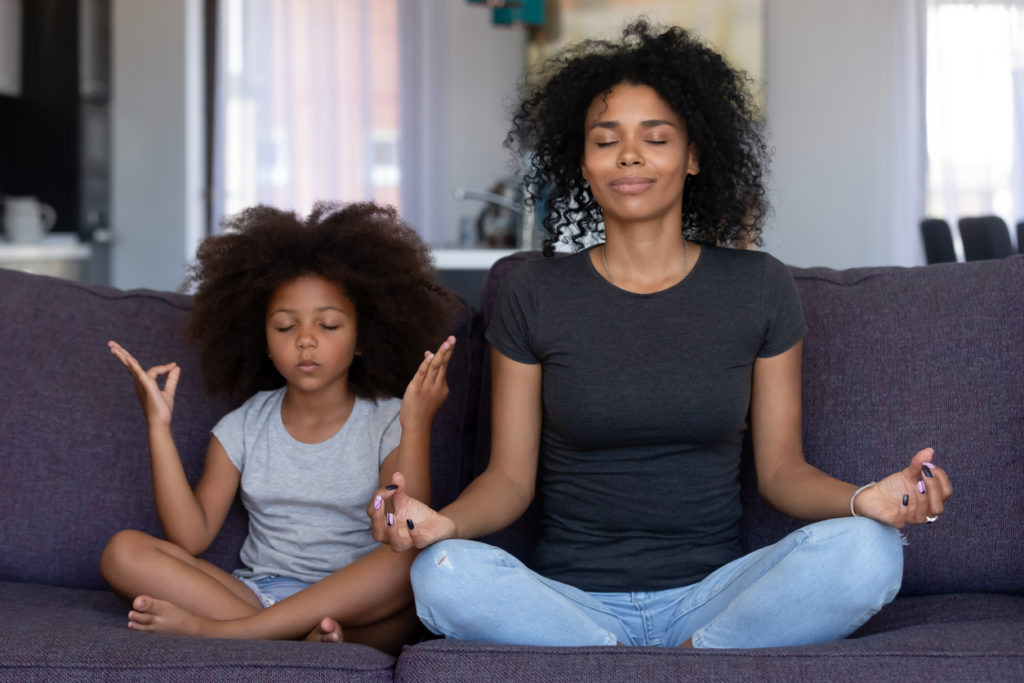mother and daughter meditating at home together
