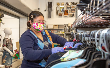 Woman shopping at Goodwill store wearing mask and gloves