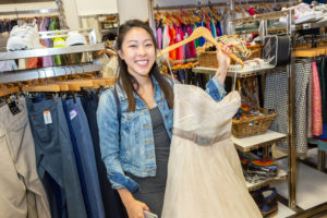 Customer holding up dress in front of men's and kid's section