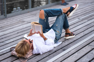 woman reading; wearing ripped jeans