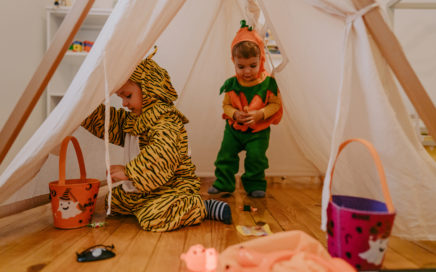 Children in Halloween costumes; looking for candy in their fort at home